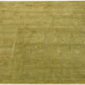 Peut inclure: Un tapis rectangulaire de couleur vert olive uni avec une texture à poils courts et denses. Le tapis présente un motif de bordure ton sur ton subtil qui crée un effet de cadre rectangulaire sur la surface principale du revêtement de sol.