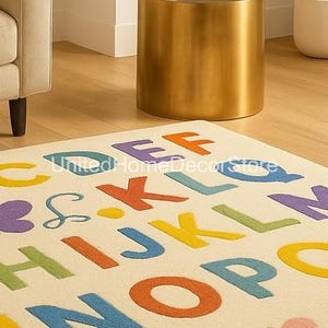 K&ouml;nnte beinhalten: Ein cremefarbener Teppich mit gro&szlig;en, farbenfrohen Buchstaben des Alphabets. Die Buchstaben sind in verschiedenen Farben gehalten, darunter Orange, Blau, Gelb, Gr&uuml;n und Lila. Der Teppich hat ein weiches, strukturiertes Aussehen und ist f&uuml;r ein Kinderzimmer geeignet.