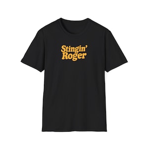 May include: Black t-shirt with the text "Stingin' Roger" in yellow, a playful and eye-catching design. The shirt is a classic crew neck style, perfect for casual wear. The text is in a bold, retro font.