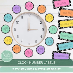 May include: A round wall clock with a light wood frame and white face, surrounded by circular labels showing minutes from :00 to :55 in various colors with black speckled borders, and rectangular labels with time phrases like O'CLOCK and HALF PAST.
