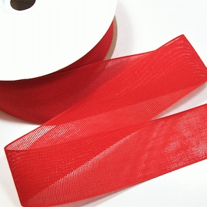 May include: A spool of bright red sheer ribbon. The ribbon is unwound, revealing its delicate, open weave texture. The ribbon is a vibrant, solid color, perfect for crafting, gift wrapping, or decorative purposes.