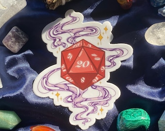 May include: A red twenty-sided die with white numbers is surrounded by purple and gold smoke. The die is on a white sticker with a blue background.