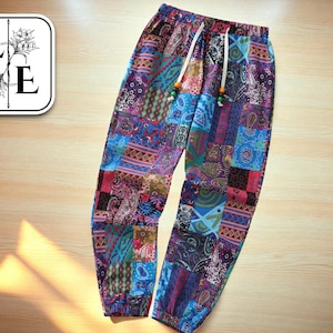 Op de afbeelding: Kleurrijke patchworkbroek met een tailleband met trekkoord. De broek heeft verschillende patronen in blauwe, paarse, rode en groene tinten. Het trekkoord heeft decoratieve kralen. De broek is gemaakt van een lichte stof.