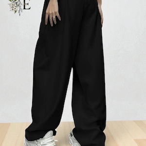 Peut inclure: Pantalon noir à jambes larges et taille haute. Le pantalon est associé à des baskets blanches. L'image présente également les lettres "E" et "E" dans un motif floral décoratif.