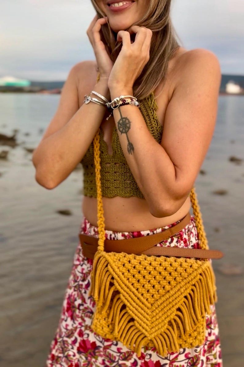 Mustard yellow boho macrame handbag with triangle flap. It us styled on a girl with biho outfit standing in the river.