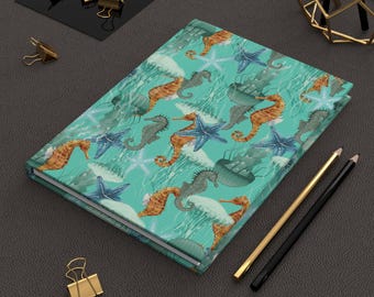 Cuaderno de tapa dura con escena oceánica, acabado mate.