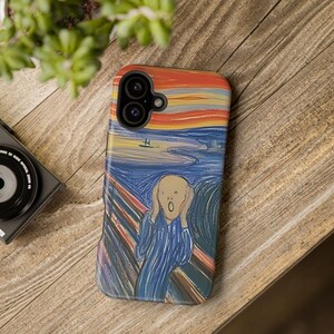 May include: A phone case featuring Edvard Munch's "The Scream" painting. The case has a colorful design with a screaming figure against a vibrant sky. The case is on a wooden surface.