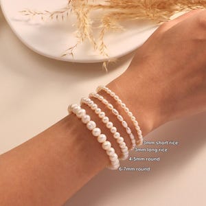 May include: Five pearl bracelets of different sizes and shapes are shown on a wrist. The bracelets include 3mm short rice, 3mm long rice, 4-5mm round, and 6-7mm round pearls. The pearls are white and have a glossy finish.