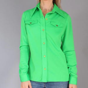 Camicetta vintage anni '70, verde in poliestere con ampio colletto a punta e tasche decorative sul petto.