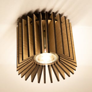 Könnte beinhalten: Eine moderne Deckenleuchte aus Holz mit einer runden Lichtquelle in der Mitte. Die Leuchte hat ein einzigartiges Design mit mehreren Holzlamellen, die ein geometrisches Muster bilden.