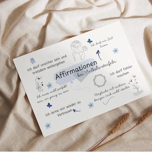 Könnte beinhalten: Eine weiße Karte mit dem deutschen Text "Affirmationen bei Selbstzweifeln" und Affirmationen auf Deutsch, mit floralen und Schmetterlingsillustrationen. Die Karte liegt auf einer beigen Stoffoberfläche.