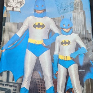May include: A vintage sewing pattern for a Batman costume. The pattern is for sizes A and includes instructions for making a cape, mask, and suit. The pattern is from Butterick and has the number 4201 on it.