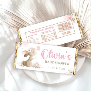 May include: Two chocolate bar wrappers with a baby shower theme. One wrapper features a bunny with a flower crown and a butterfly. The other wrapper has a nutrition facts label and the text "Thanks for commig!" and "HAVE FUN!"