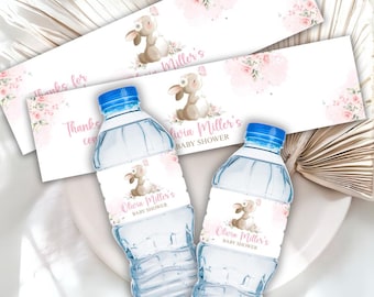 May include: Two water bottles with blue caps and labels that read "Olivia Miller's BABY SHOWER" and feature a cartoon bunny with floral accents. Additional matching labels are visible, with text "Thanks for" and floral designs.
