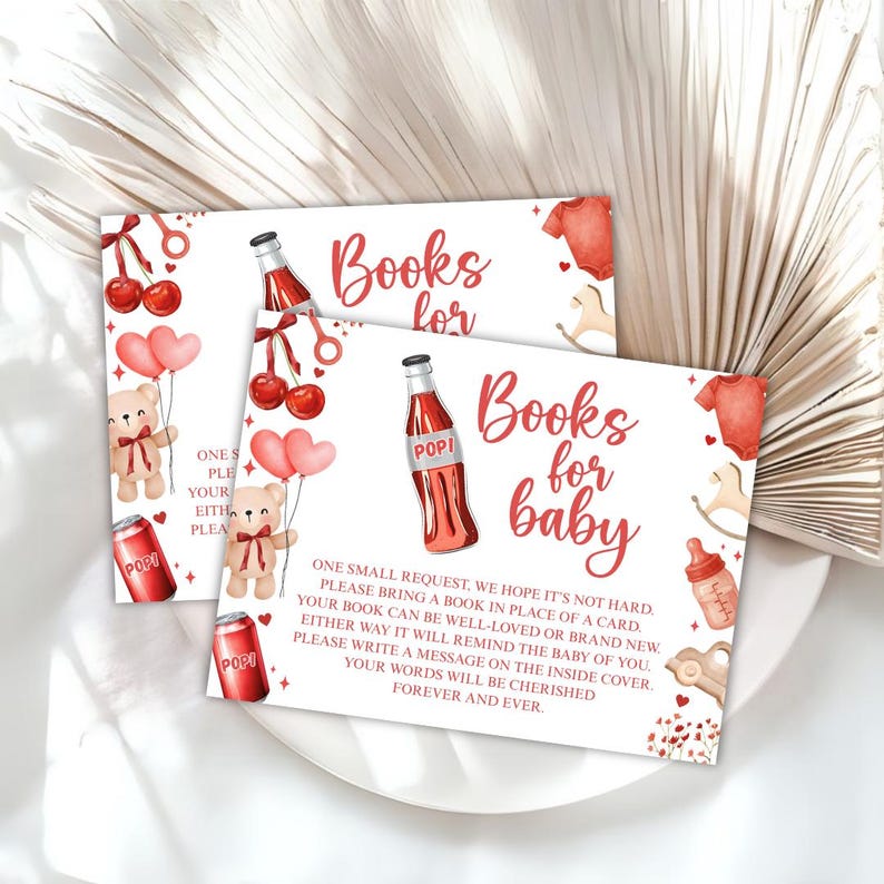 May include: Two baby shower invitation cards with a watercolor design. The cards feature the text "Books for baby" in red script, along with illustrations of teddy bears, soda bottles, and baby clothes. The cards are on a white plate.
