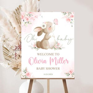 Puede incluir: Un letrero de bienvenida para baby shower con una ilustración de acuarela de un conejito, flores y una mariposa. El letrero dice "Oh baby" y da la bienvenida a Olivia Miller. También se muestra la fecha 10.28.20XX.