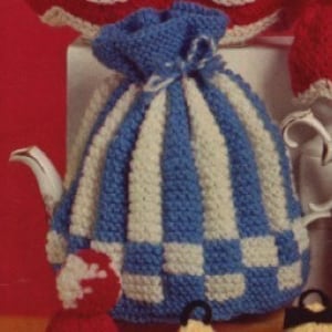 May include: A blue and white striped teapot cosy with a checkered pattern at the bottom. The cosy has a gathered top and a small red heart-shaped appliqué.