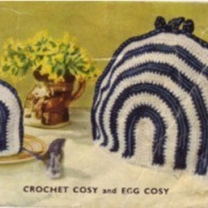 Puede incluir: Un posavasos de ganchillo a rayas blancas y azules y un posavasos de huevo a juego más pequeño. El texto "CROCHET COSY and EGG COSY" está impreso debajo de los artículos.