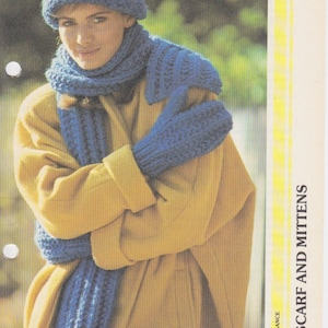 Könnte beinhalten: Ein blaues Strickset aus Mütze, Schal und Fäustlingen. Die Mütze ist ein lockerer Beanie-Stil. Der Schal ist lang und breit. Die Fäustlinge sind fingerlos.