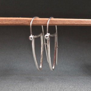 May include: A pair of silver hoop earrings with a small ball at the top of each hoop.