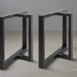 May include: Two black metal table legs with a criss-cross design. The legs are made of square tubing and have a simple, modern style.