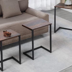 May include: Three brown wooden side tables with black metal frames. The tables are on a light grey rug. The tables are all the same size and shape.