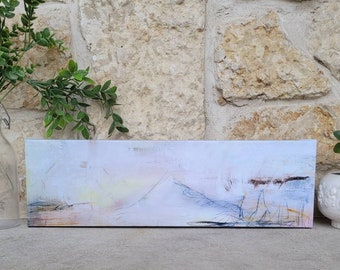 May include: Abstract landscape painting on canvas with shades of white, blue, and yellow. The painting has a textured surface and is framed in a simple wooden frame.