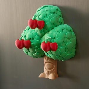May include: A whimsical, three-dimensional tree magnet with a light brown trunk and vibrant green leaves. Clusters of bright red cherries adorn the tree. The magnet is designed to resemble a cartoon-like illustration.