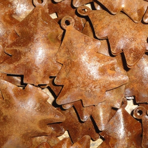 May include: A close-up of a pile of rustic, brown metal Christmas tree ornaments. The ornaments are made of thin metal and have a distressed, rusty finish.