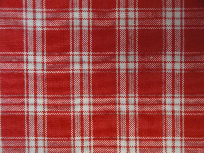 May include: Close-up of a red and white plaid fabric. The pattern consists of intersecting vertical and horizontal white lines against a red background, creating a grid-like design. The fabric appears to be woven.