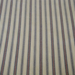 May include: Cream-coloured fabric with vertical stripes. Alternating stripes of navy blue and thin red lines create a classic pattern. The fabric has a textured appearance, suggesting a woven material.