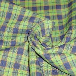 May include: Green and blue plaid fabric with a yellow stripe. The fabric is folded and textured.