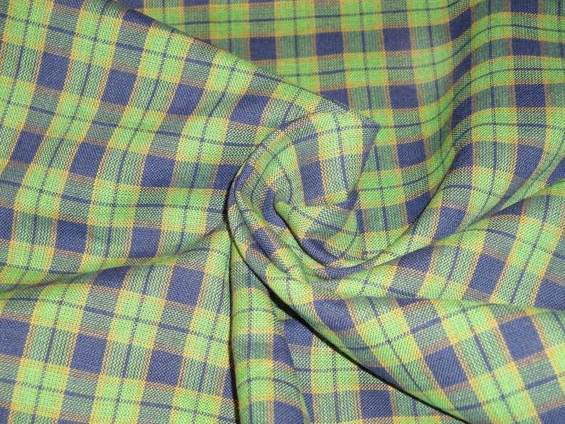 May include: Green and blue plaid fabric with a yellow stripe. The fabric is folded and textured.