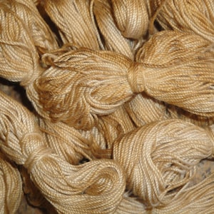 May include: A close-up of a pile of beige yarn. The yarn is soft and fluffy, and it is perfect for knitting or crocheting.