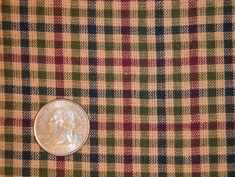 May include: A close-up of a tan, green, red, and black plaid fabric with a US quarter on top of it.