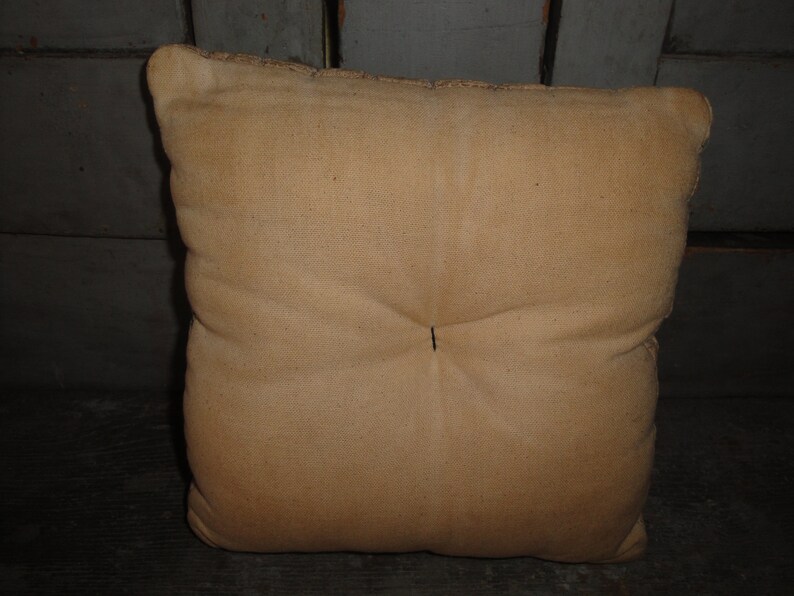 May include: A plain, off-white, square pillow with a single button in the center.