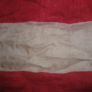 Op de afbeelding: Een rood, wit en rood gestreepte stof met een textuur.