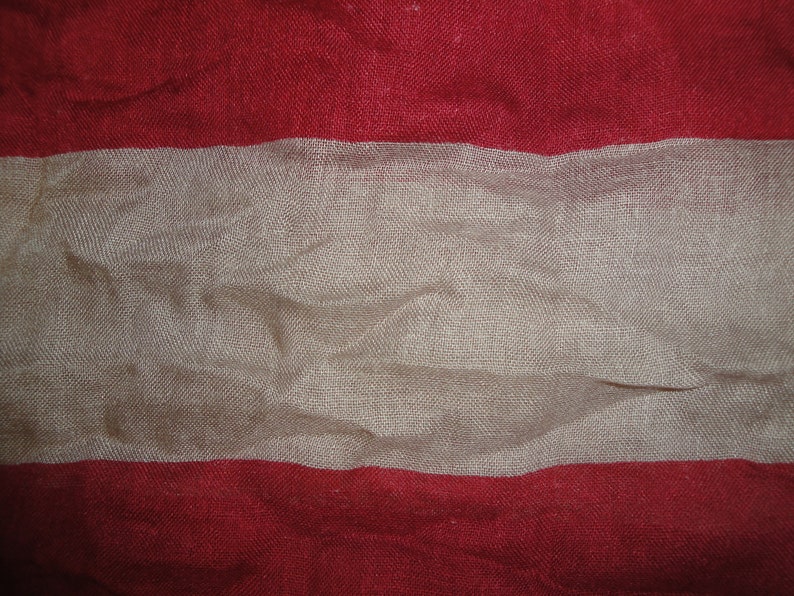 Op de afbeelding: Een rood, wit en rood gestreepte stof met een textuur.