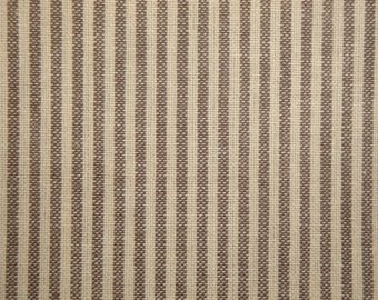 May include: Close-up of a fabric with vertical stripes. The stripes alternate between a light beige and a darker brown, creating a textured pattern. The fabric appears to be woven, with a slightly rough surface.