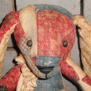 May include: A handmade patchwork fabric bunny toy with red, white, and blue fabric. The bunny has black button eyes and a black stitched nose.