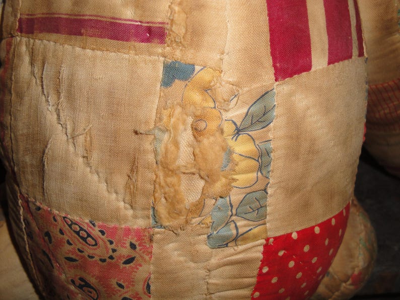 May include: A patchwork quilt with a variety of fabrics, including floral prints, stripes, and paisley patterns. The quilt is made of different shades of brown, red, and white.