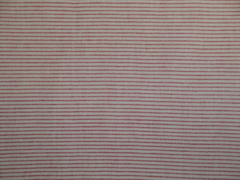 May include: Close-up of a fabric with a repeating pattern of thin, horizontal red stripes on a white background. The stripes are evenly spaced and create a textured appearance, suitable for various textile projects.