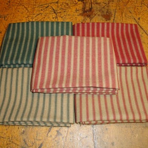 May include: Six fabric squares with a striped pattern. The squares are folded in half and stacked on top of each other. The stripes are red and tan, green and tan, and red and tan.