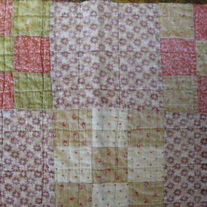 May include: A patchwork quilt with a variety of floral patterns in shades of pink, green, and white.