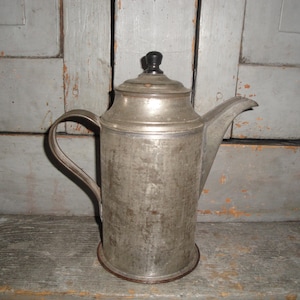 May include: A white ceramic mug with a black handle and the text "But First, Coffee" in a black, bold font. The mug is on a white surface.