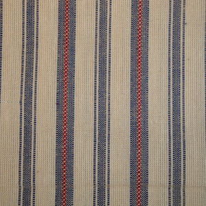May include: Close-up of a woven fabric with vertical stripes. Alternating stripes of navy blue and red are set against a cream-coloured background. The texture of the fabric is visible, suggesting a natural fibre.