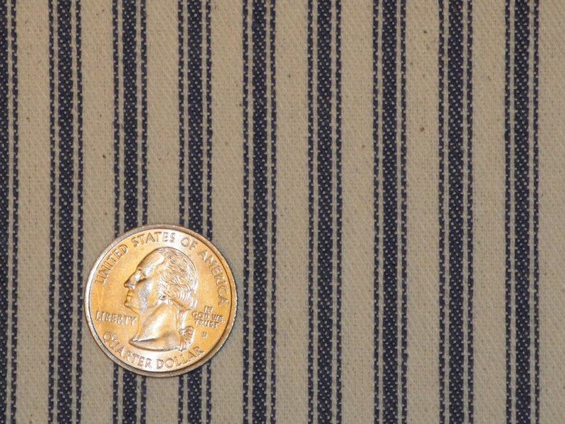 Pode incluir: Close-up de um tecido bege com finas listras azul-escuro. Uma moeda de 25 centavos de d&oacute;lar americano &eacute; colocada no tecido para escala.