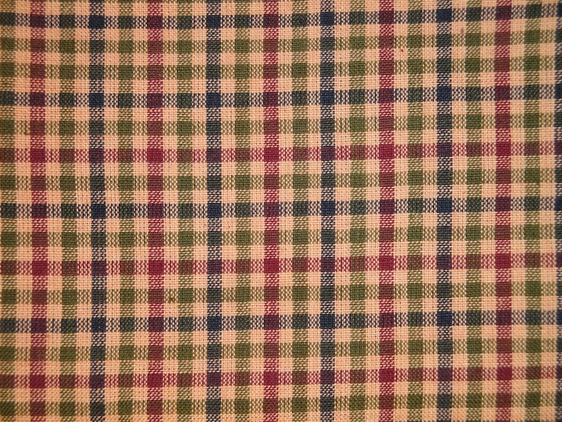 May include: A close-up of a fabric with a plaid pattern in shades of beige, green, red, and blue.