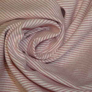 May include: Close-up of a white fabric with thin, evenly spaced red stripes. The fabric is gathered and folded, creating a swirling pattern. The stripes run parallel to each other, adding texture and visual interest to the textile.