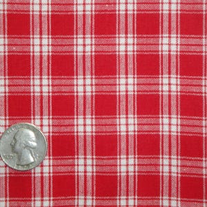 May include: Close-up of red and white plaid fabric. The fabric has a classic checkered pattern with a quarter coin for size reference. The fabric is likely cotton or a similar material.